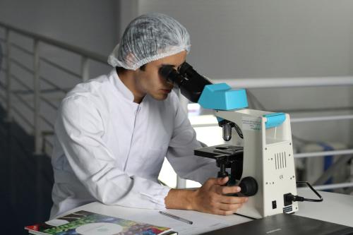investigación cm masculino Un investigador observa una muestra a través de un microscopio