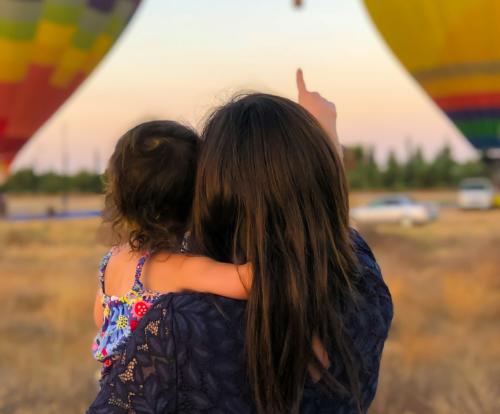 dia de la madre 2 Una madre coge en brazos a su hija mientras despegan globos aerostáticos de fondo